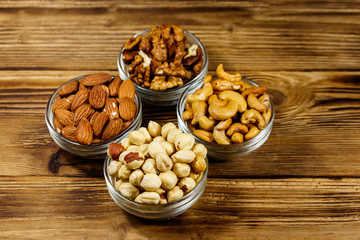 Assortment of nuts on wooden table. Almond, hazelnut, walnut and cashew in glass bowls. Healthy eating concept