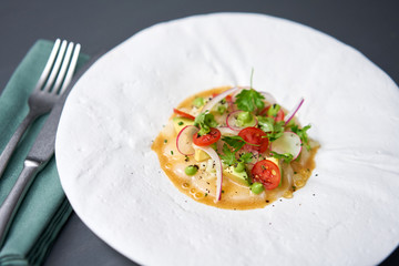 Tartar from scallop with avocado, cherry tomatoes, radishes and onion. Dish in the restaurant from raw seafood.
