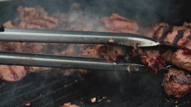 Chef takes ready-fried pieces of meat from bbq grill in slow motion. Food and Catering. Traditional national marinated dish Shashlik or shish kebab is fried on barbecue. Close up