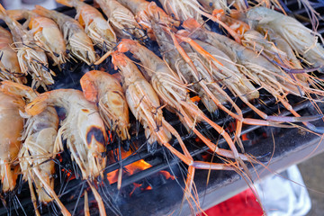 Grilled shrimps on the flaming grill with flames in background in Thailand market