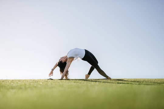 Young woman does yoga in grassy field