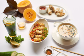 Oriental dinner from soup with seeds, tempura shrimps and noodles with vegetables preparing for client. Three dishes lunch with mint tea ready for eating.