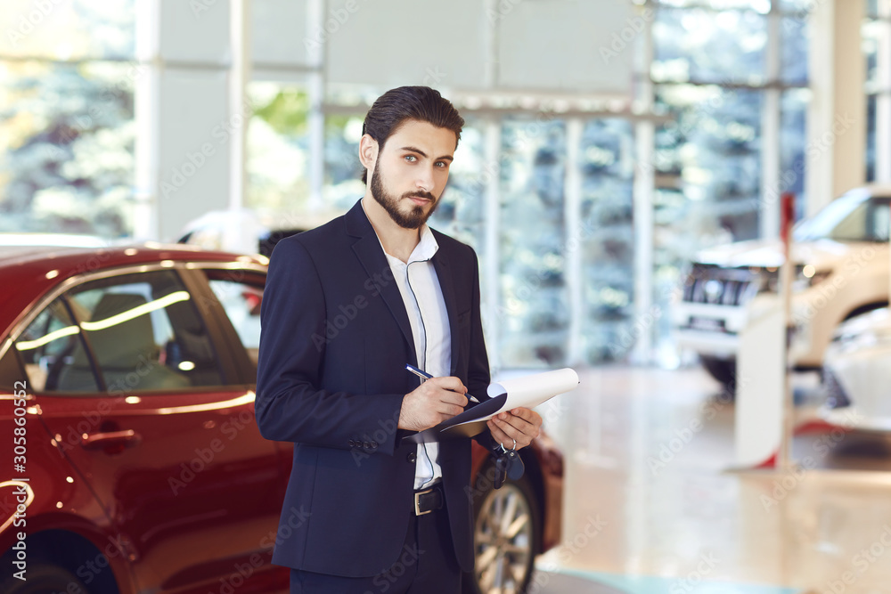 Wall mural a car dealer standing in a showroom.