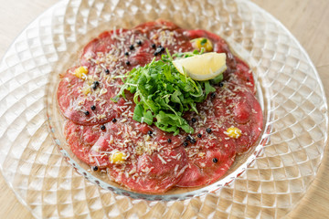 Beef carpaccio with balsamic caviar and Parmesan cheese on wooden table background. Restaurant menu, natural and organic food concept.