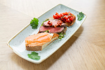 Bruschetta with beef, tomatoes and salmon. Various snacks and antipasti on the table. Restaurant menu. Italian cuisine