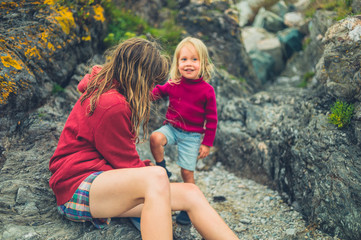 Mother helpong toddler put on shoes at the beach
