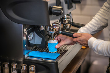 Barista using coffee machine while making coffee for customer