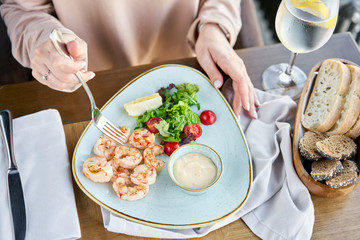 Grilled Argentine shrimp with mango-jalapeno sauce. Lunch in a restaurant, a woman eats delicious and healthy food. Delicious fresh seafood prawns with fresh vegetables and lime. Cream sauce
