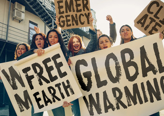 Young woman with poster in front of people protesting about climate changing on the street. Meeting...