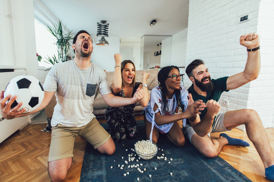 Very Excited Friends Having Fun By Watching Football Match, Drinking Beer And Eating Popcorn At Home