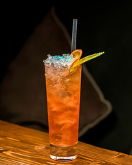 orange cocktail garnished with ice and orange slice