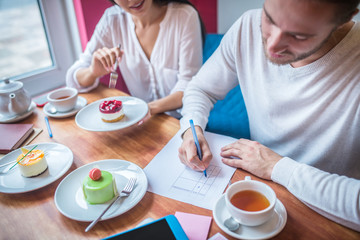 Obraz na płótnie Canvas Businessman making notes while revising desserts for their menu