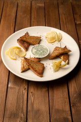triangular fried bread with sauce with dill and lemon