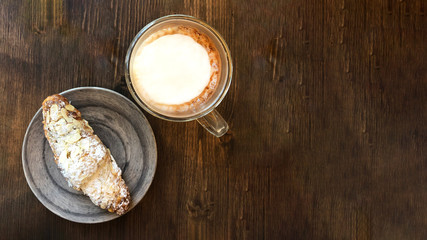 Cacao with croissant on wood table.