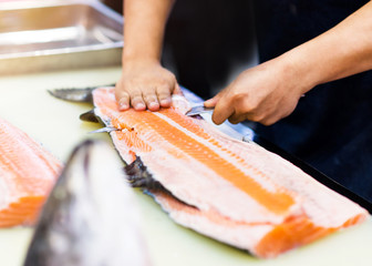 chef using a knife to slice salmon fillet , chef cut the salmon in restaurant