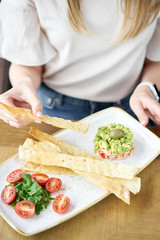 Woman eats salad crab, avocado, citrus oil, spices. Crab meat with matzo on white plate for cooked seafood.