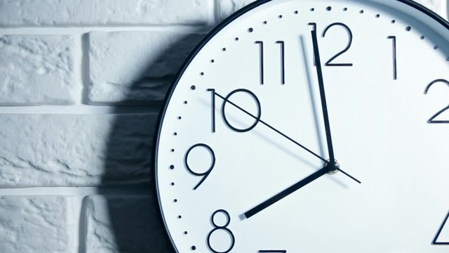 Single white clock hanging on a brick wall