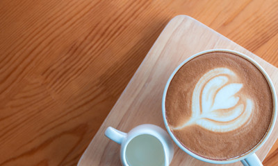 Latte coffee cup with latte art on wooden table in coffee shop.