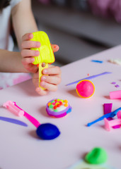 Child hands playing with colorful clay. Homemade plastiline. Girl molding modeling clay. Homemade clay. Child playing and creating from play dough.