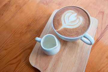Latte coffee cup with latte art on wooden table in coffee shop.