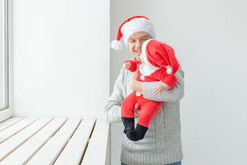 Fatherhood and holidays concept - Father with his baby boy wearing Santa hats celebrating Christmas