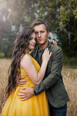 Pregnant girl and a young guy on a wheat field.