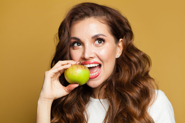 Diet concept and healthy eating concept. Young woman with apple fruit on bright yellow background