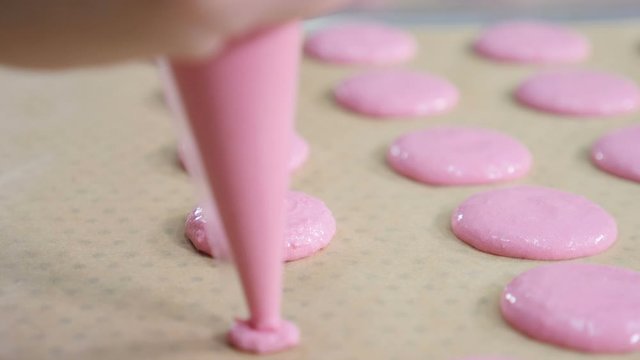 Making Caramel Macaroons. cooking, food and baking concept - chef with confectionery bag squeezing cream filling to macarons shells at pastry shop. Slow motion. hd