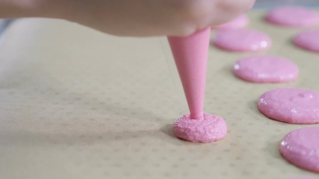 Confectioner Making Caramel Macaroons. cooking, food and baking concept - chef with confectionery bag squeezing cream filling to macarons shells at pastry shop. close up. Slow motion. hd