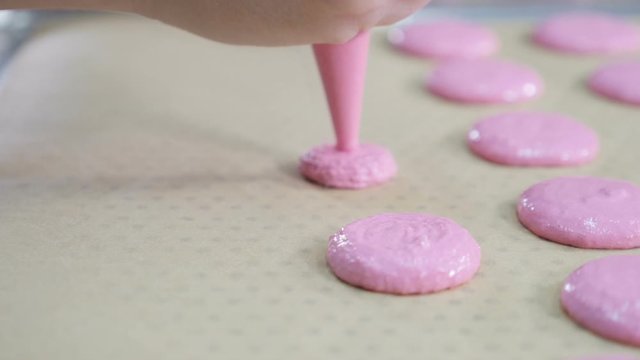 Confectioner Making Caramel Macaroons. cooking, food and baking concept - chef with confectionery bag squeezing cream filling to macarons shells at pastry shop. close up. Slow motion. hd