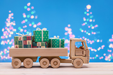 Truck with Christmas and New Year's gifts in boxes. Blue background, luminous Christmas trees. The concept of winter holidays.