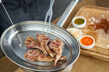 The waiter is butchering with a knife. Rack of lamb , grilled meat with bone. Barbecue restaurant menu, a series of photos of different meats