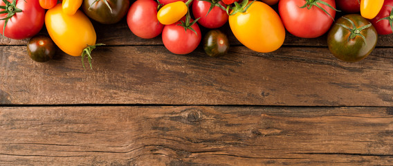 Overhead shot of various kinds of tomatoes on rustic wooden table with copyspace. Food background....