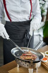 The waiter is butchering with a knife. Rack of lamb , grilled meat with bone. Barbecue restaurant menu, a series of photos of different meats