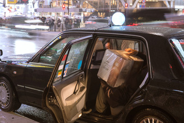 Japanese man getting into taxi on rainy night　雨の夜にタクシーに乗り込む男性