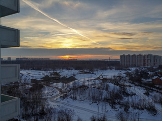 View from the height of the orange-red sunset over the city covered with snow