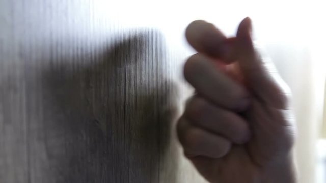 Male hand knocking at wooden door, visitor or guest at the door.