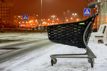 The concept of the modern shopping center. Photo of a street of a store with a stroller against the background of the evening city with lights.