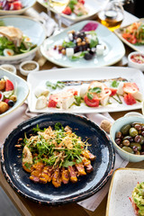 Roast beef, vegetables, carrot and oyster sauce. Sliced grilled beef barbecue Striploin steak and salad with arugula. Various snacks and antipasti on the table. Restaurant menu.