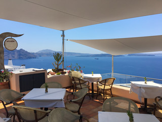 Greek tavern with table and chairs on a background of blue sea, sky and mountains