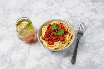 Spaghetti bolognese and lemonade on grey concrete background
