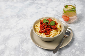 Spaghetti bolognese and lemonade on grey concrete background
