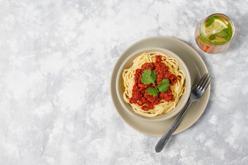 Spaghetti bolognese and lemonade on grey concrete background