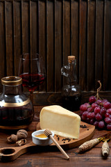 piece of parmesan cheese served with grape and wine