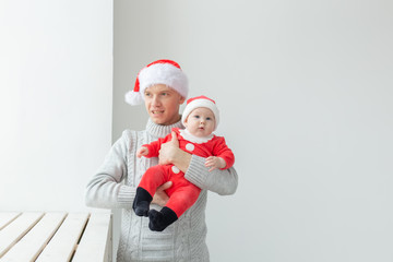 Fatherhood and holidays concept - Father with his baby boy wearing Santa hats celebrating Christmas