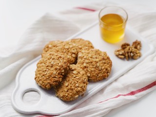 oatmeal cookies, honey and nuts on a white towel. Rustic style. White background. High key in food pictures