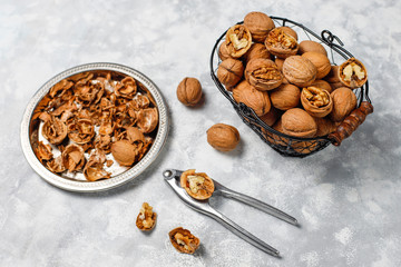 Whole walnuts in shell in food metal basket, walnut kernels. Top view on concrete background
