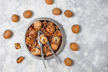 Whole walnuts in shell in food metal basket, walnut kernels. Top view on concrete background