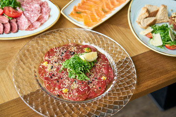 Beef carpaccio with balsamic caviar and Parmesan cheese. Various snacks and antipasti on the table. Italian cuisine Restaurant menu, natural and organic food concept.