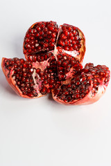 Ripe cut juicy red pomegranate on a white background.